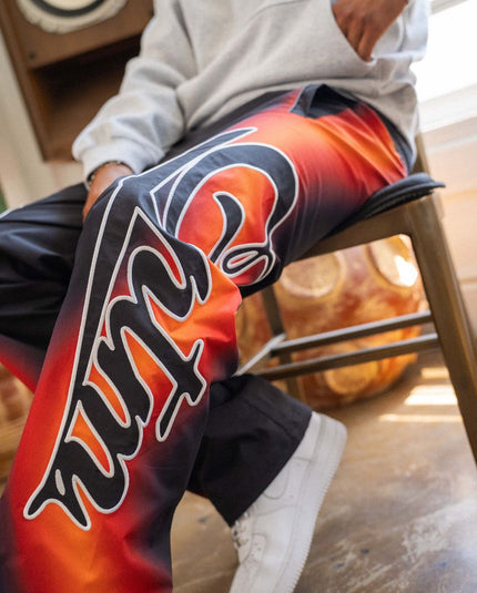 Person wearing a colorful jacket with a prominent logo, sitting on a chair.