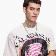 Man wearing a white t-shirt with a colorful graphic design on a plain background