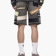 Person wearing gray shorts with patches and a dark shirt on a white background