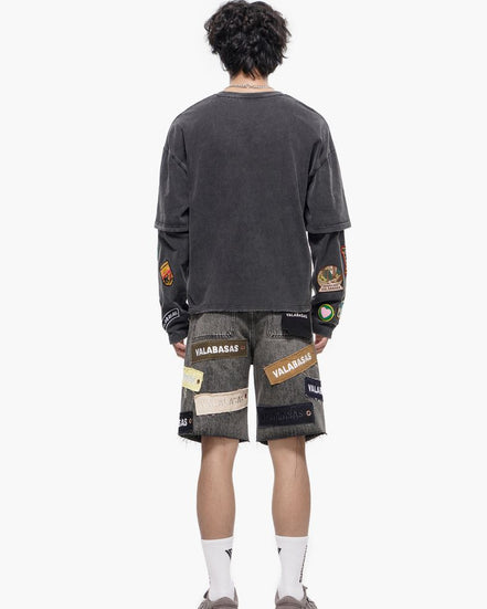 Person wearing a dark gray long-sleeve shirt and patterned shorts on a white background