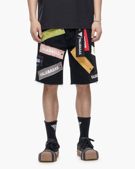 Person wearing black shorts with colorful brand patches on a white background