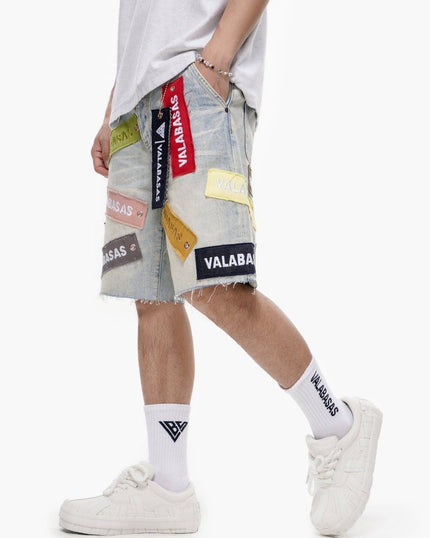 Person wearing a patchwork denim skirt with brand logos and white sneakers on a white background