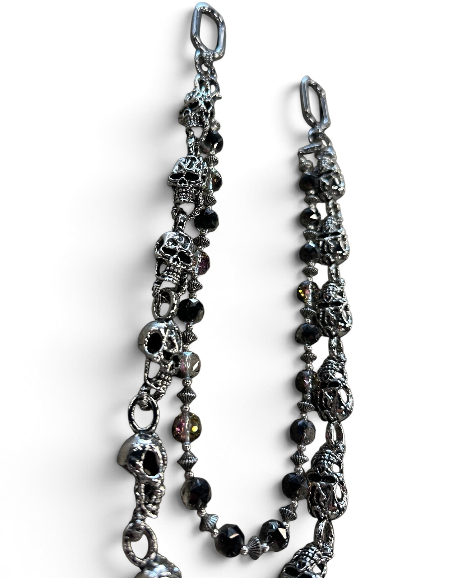 A gothic-style chain accessory featuring antique silver skull charms, faceted black beads, and small metallic spacer beads, displayed on a clean white background.
