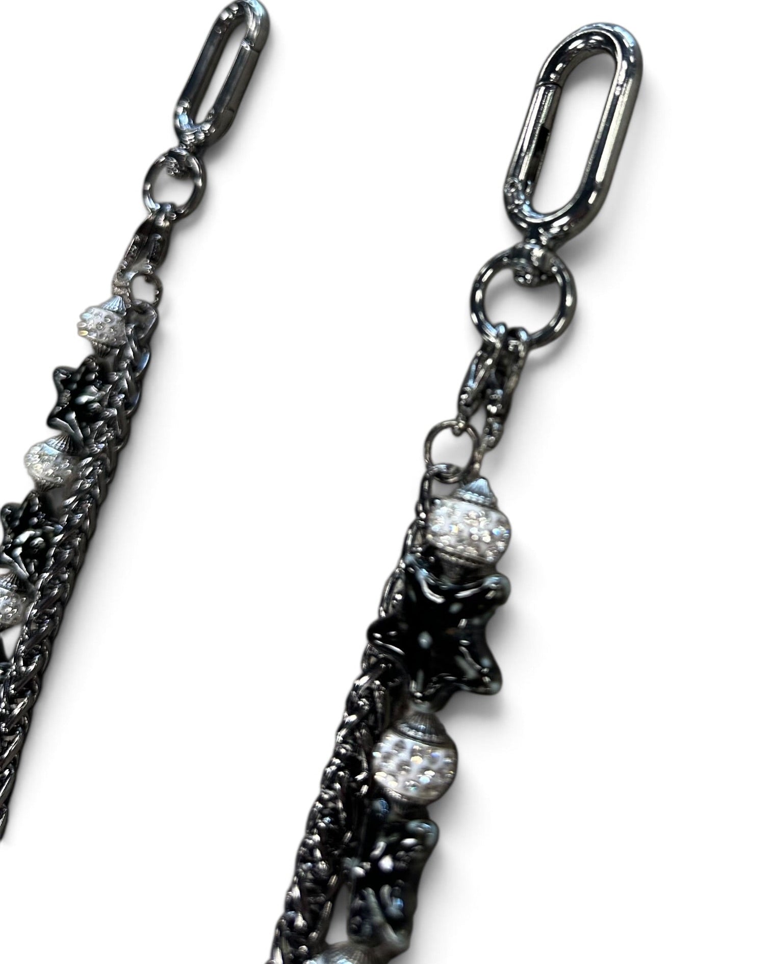 A close-up of a dark gunmetal chain accessory with star-shaped charms and clear rhinestone-covered beads, shown against a plain white background.