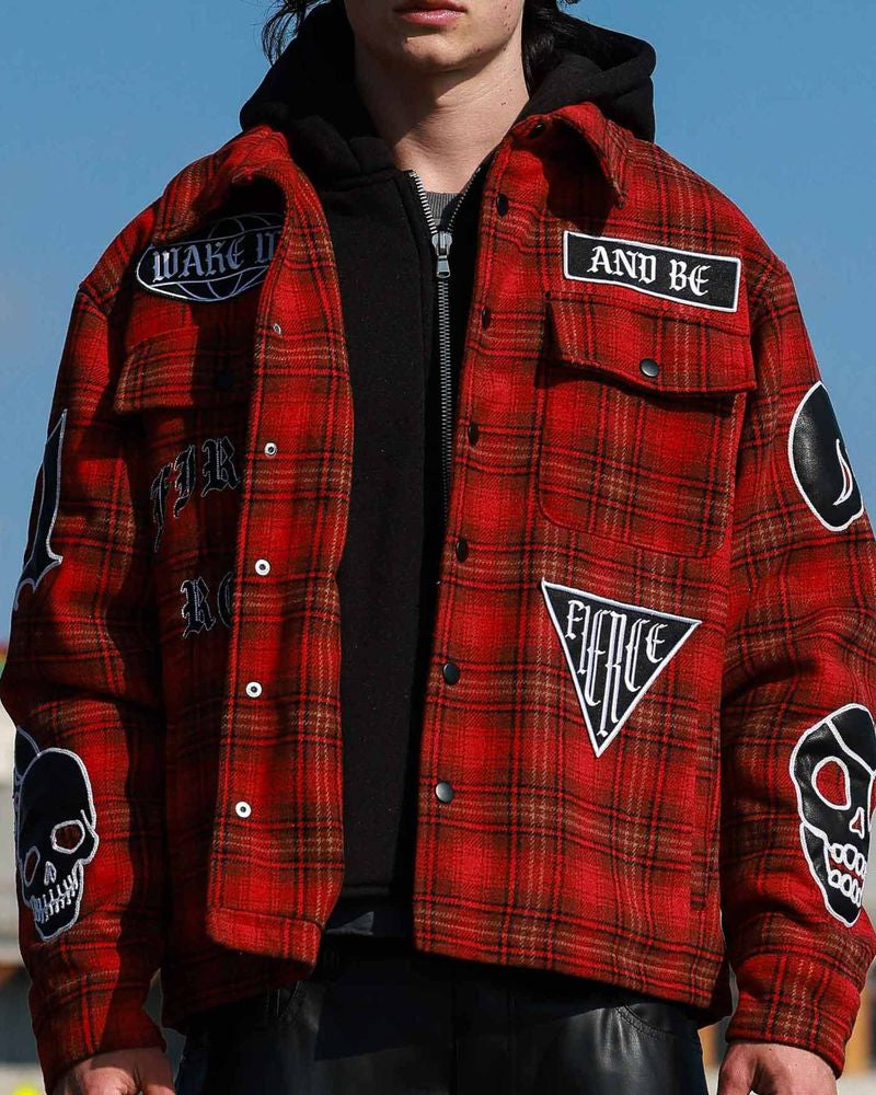 Red plaid jacket with patches worn by a person against a blue sky.