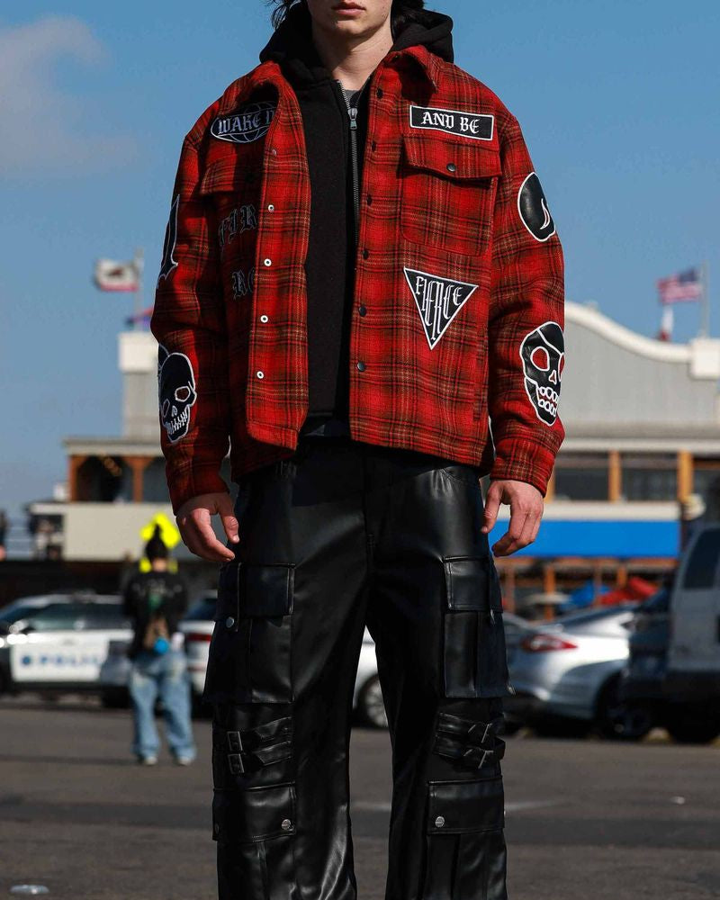 Person wearing a red plaid jacket with patches in an outdoor setting