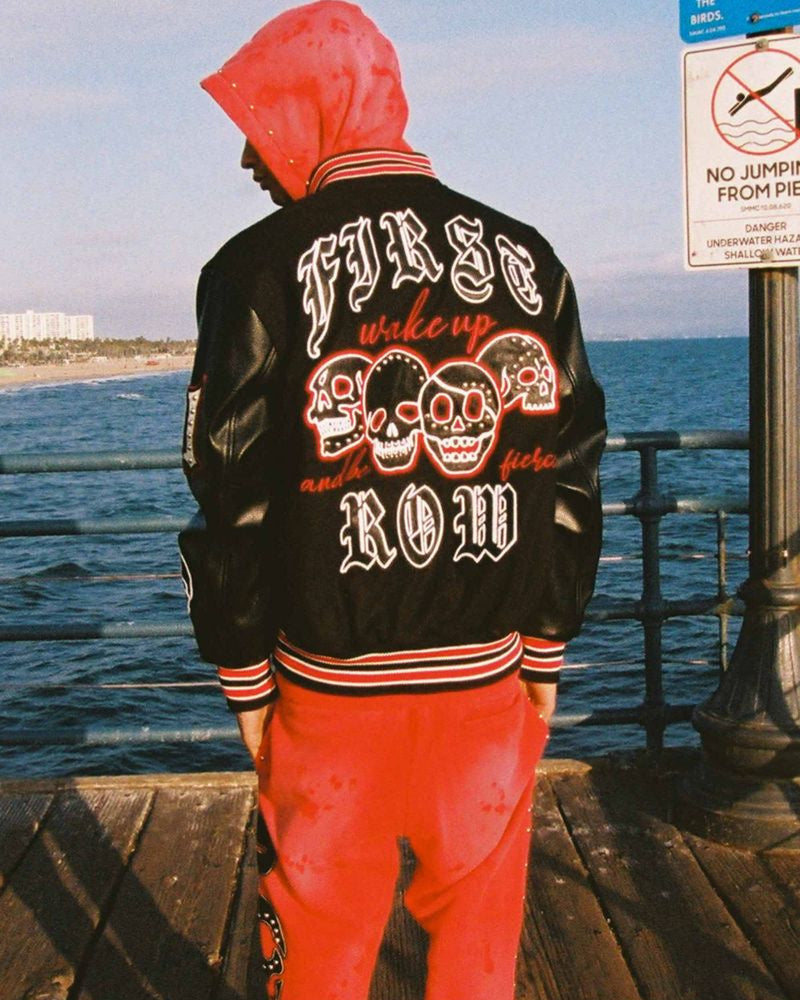 Person wearing a black jacket with red and white text by the ocean
