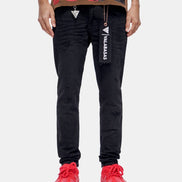 Person wearing black pants with visible branding and red shoes on a white background