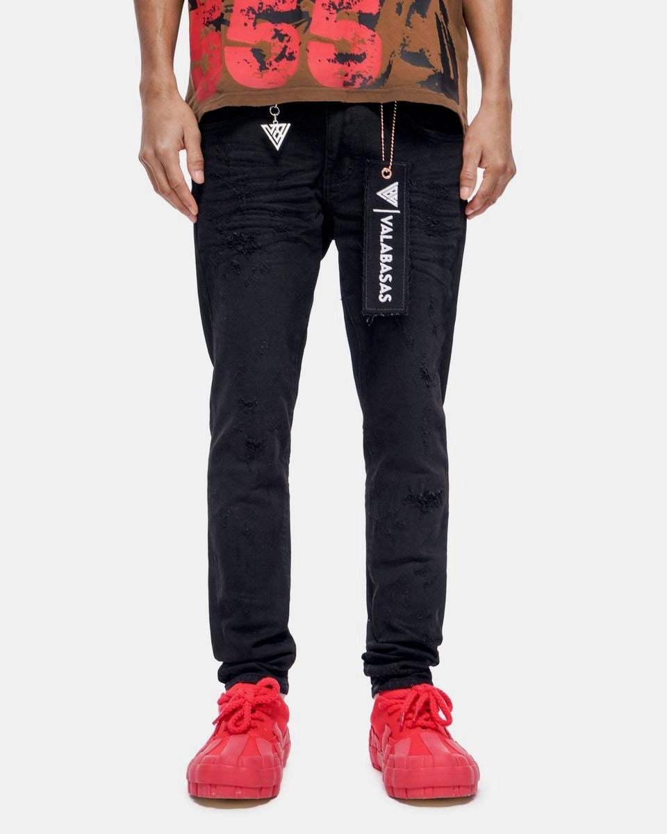 Person wearing black pants with visible branding and red shoes on a white background