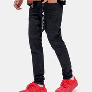 Person wearing black jeans with a visible brand logo and red sneakers on a white background
