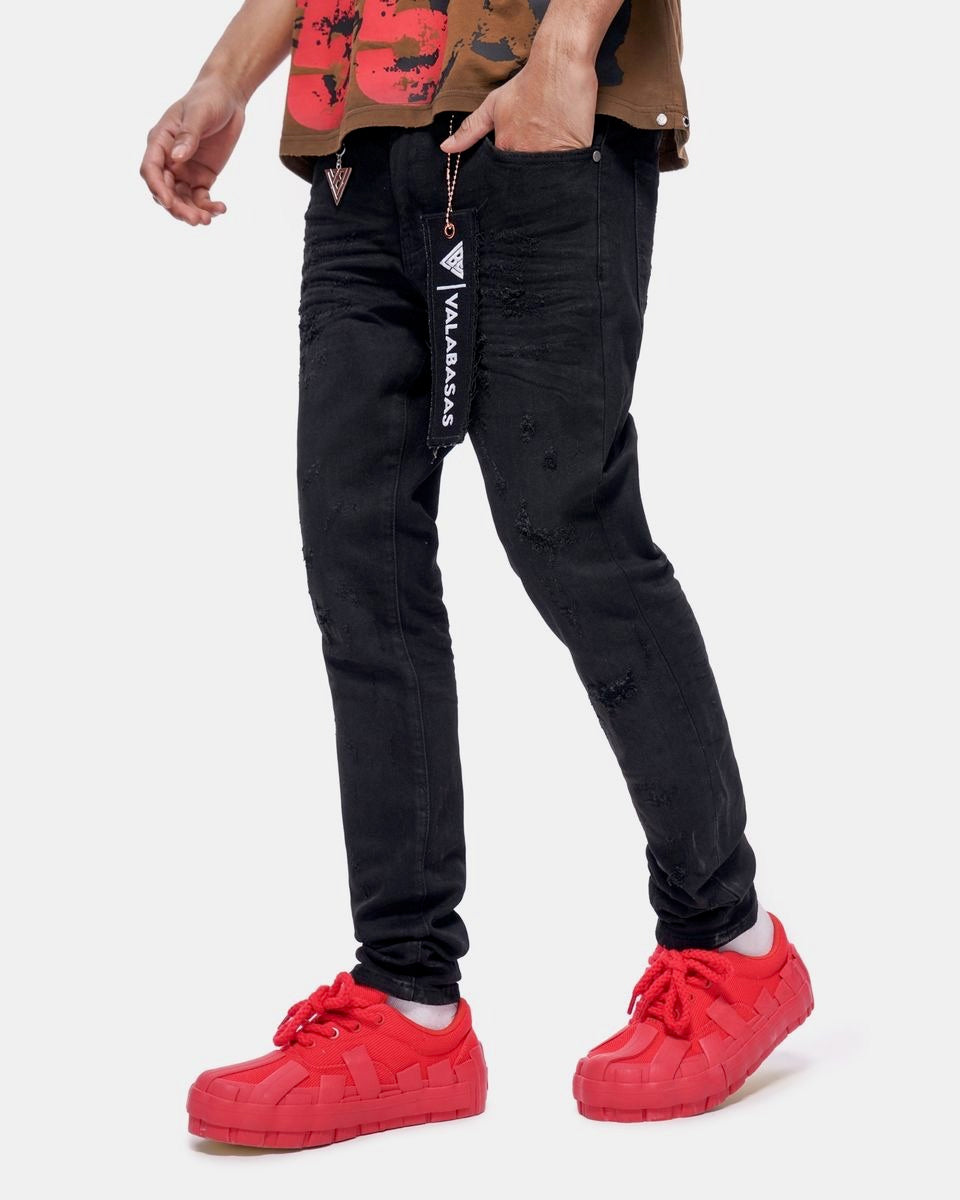 Person wearing black jeans with a visible brand logo and red sneakers on a white background