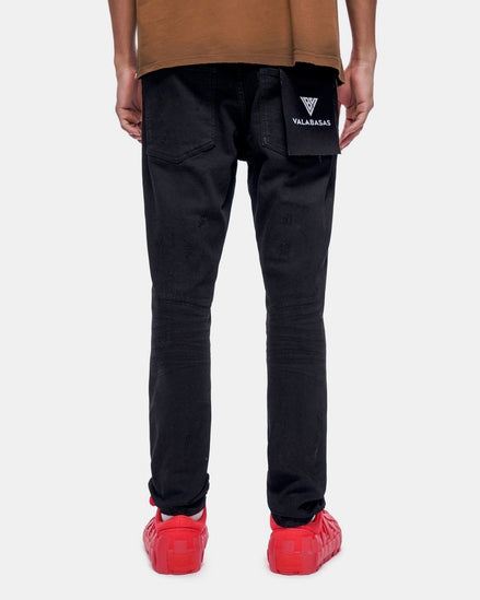 Person wearing black pants with a brand logo, brown shirt, and red shoes on a white background