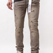 Person wearing distressed beige jeans with a white background