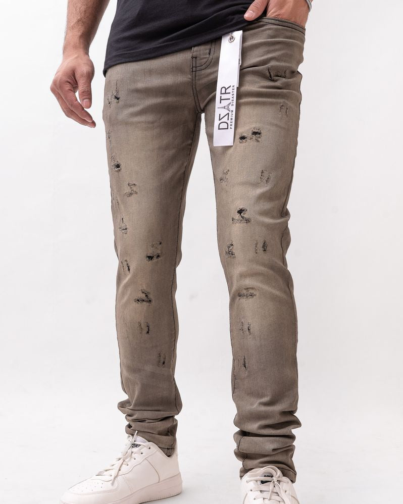 Person wearing distressed beige jeans with a white background