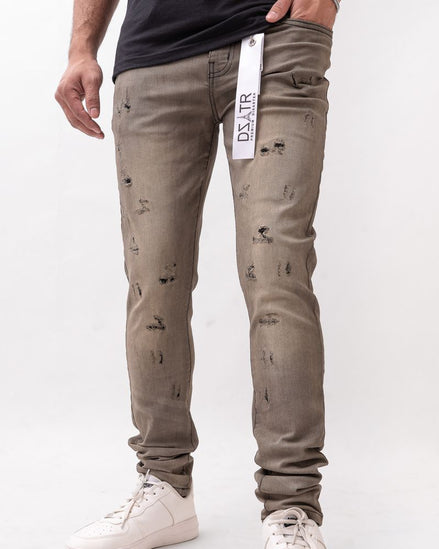 Person wearing distressed beige jeans with a white background