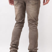 Person wearing brown slim fit jeans and white sneakers on a white background