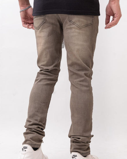 Person wearing brown slim fit jeans and white sneakers on a white background
