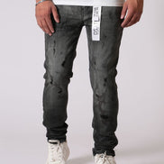 Person wearing black distressed jeans with a white label on a white background