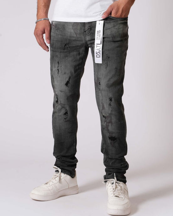 Person wearing black distressed jeans and white sneakers on a white background