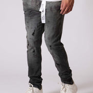 Person wearing gray distressed jeans and white sneakers on a plain background