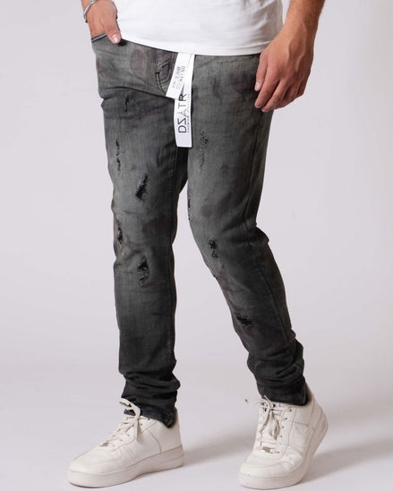 Person wearing gray distressed jeans and white sneakers on a plain background