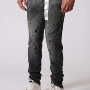 Person wearing dark distressed jeans with a white label on a light gray background