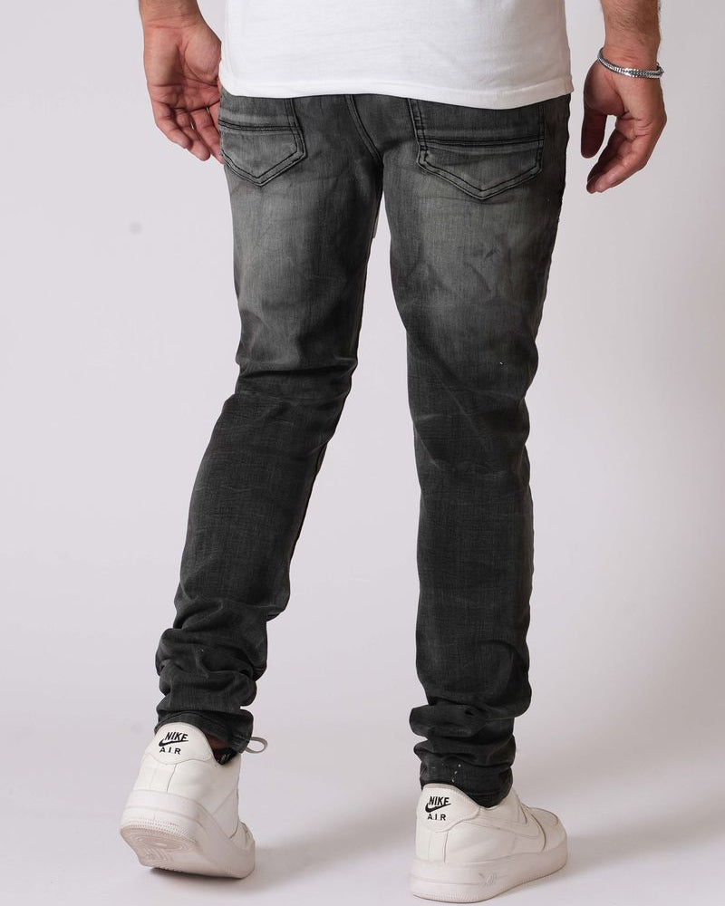 Person wearing black jeans and white sneakers on a plain background