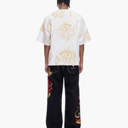 Person wearing a white t-shirt with dragon designs and black pants with red dragon designs on a white background