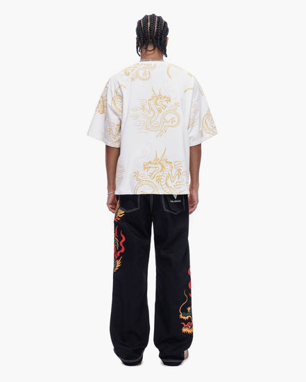 Person wearing a white t-shirt with dragon designs and black pants with red dragon designs on a white background