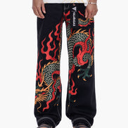 Black pants with colorful dragon design worn by a person on a white background