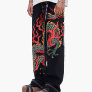 Black pants with colorful dragon design worn by a person on a white background