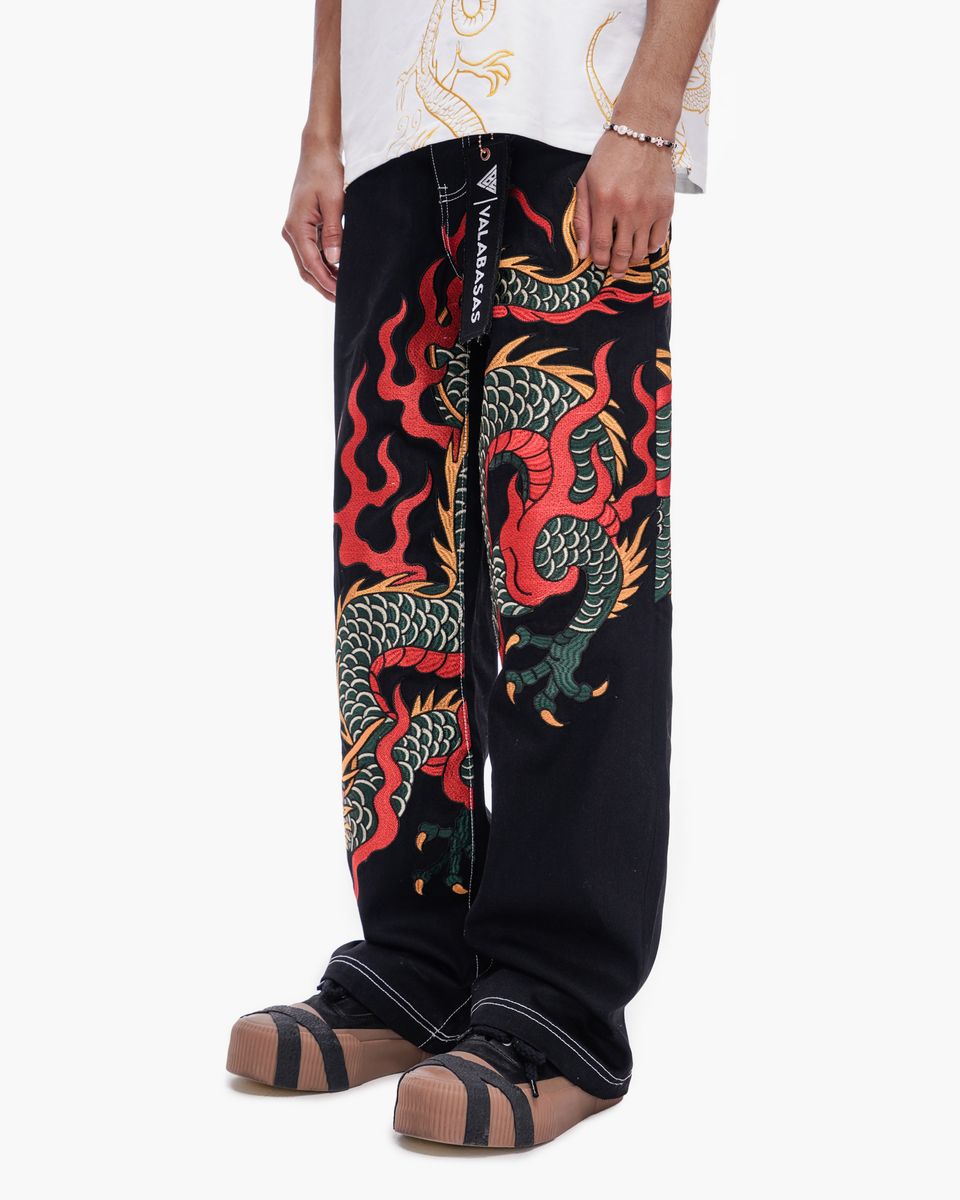 Black pants with colorful dragon design worn by a person on a white background