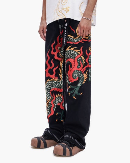 Black pants with colorful dragon design worn by a person on a white background