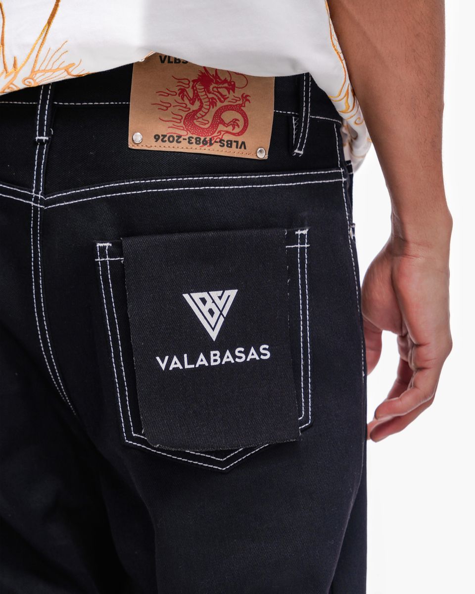 Black pants with a visible brand logo and text on the pocket, on a plain background.