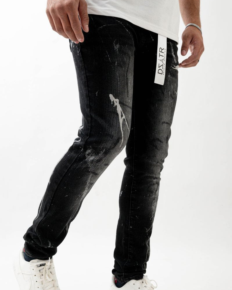 Person wearing black distressed jeans with a visible brand logo on a white background