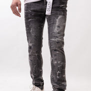 Person wearing black distressed jeans with a visible brand label on a white background