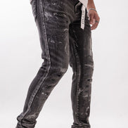 Person wearing black acid-wash jeans and white sneakers on a white background