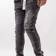 Person wearing black distressed jeans and white sneakers on a white background
