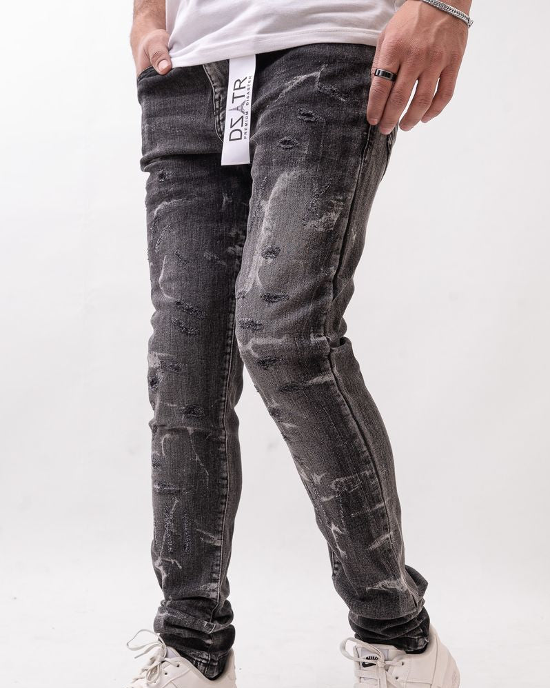 Person wearing black distressed jeans and white sneakers on a white background