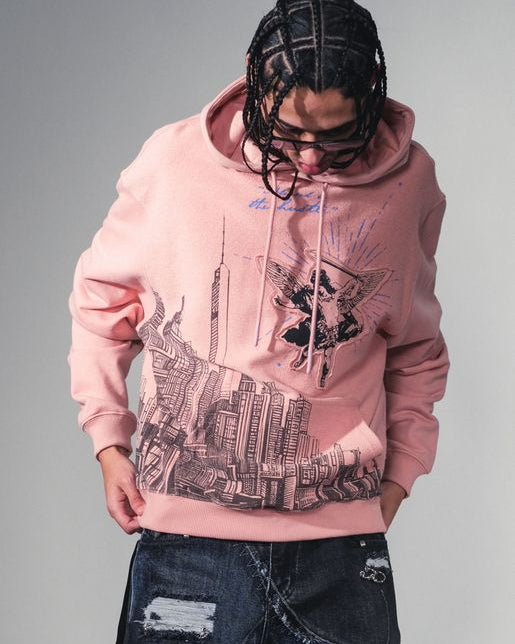 Person wearing a pink hoodie with graphic design and distressed jeans on a gray background