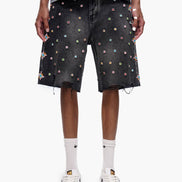 Person wearing black denim shorts with colorful dot pattern on a white background