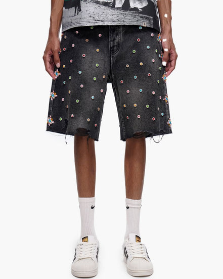 Person wearing black denim shorts with colorful dot pattern on a white background