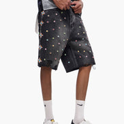 Person wearing black shorts with colorful patterns and white sneakers on a white background