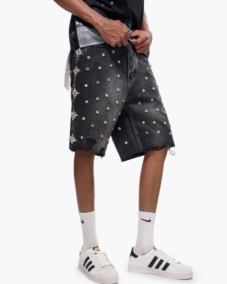 Person wearing black shorts with colorful patterns and white sneakers on a white background