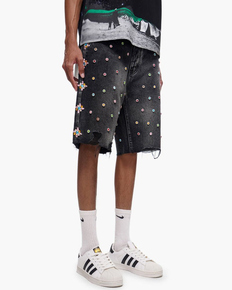 Person wearing black shorts with colorful patterns and white sneakers on a white background