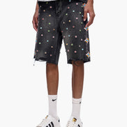 Person wearing black shorts with colorful embellishments, white sneakers, and white socks on a white background.