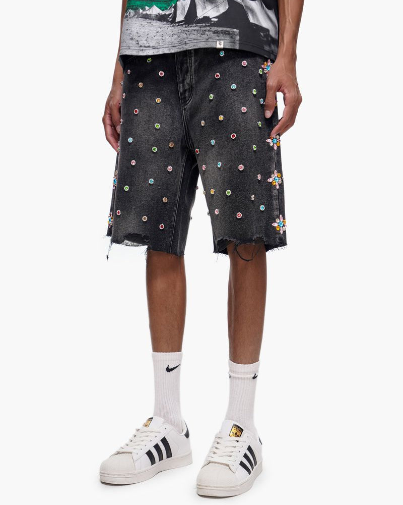 Person wearing black shorts with colorful embellishments, white sneakers, and white socks on a white background.