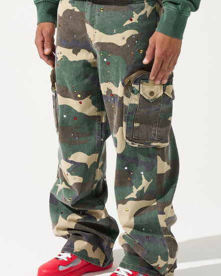 Person wearing camouflage pants with red shoes on a white background