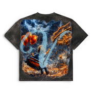 A short-sleeve t-shirt with a dark gray mineral-wash finish, featuring a large, vibrant graphic print on the back. The print depicts a whimsical fantasy scene with a person carrying a suitcase, glowing orange balloons, a Ferris wheel, and a swirling blue and white abstract shape against a dark, stormy sky.