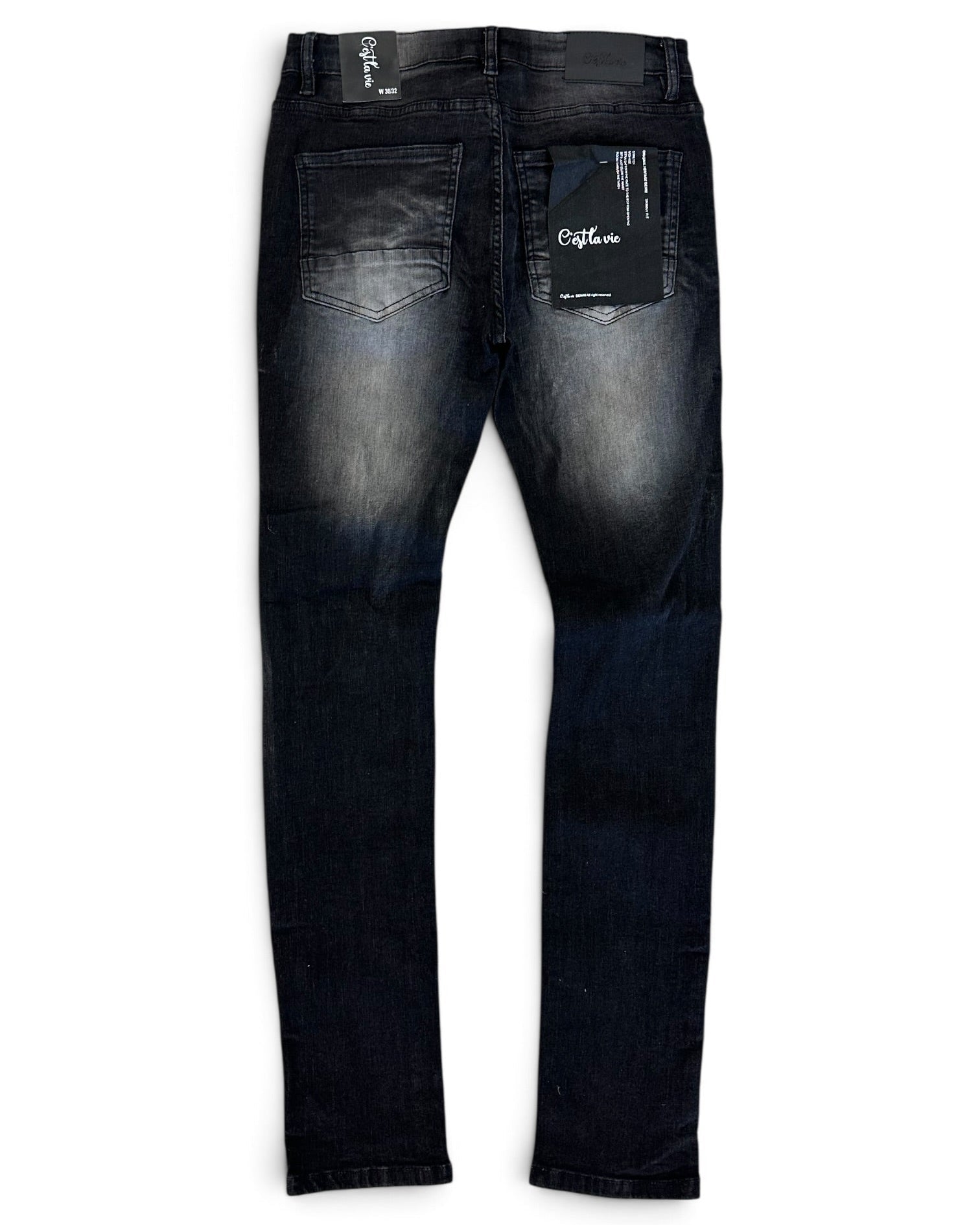 Back view of a pair of dark wash skinny jeans with a faded wash on the thighs, featuring a black brand tag on the back pocket and a white inner waistband label.